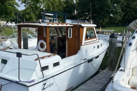 Slide: The Image of 1985 Albin 27 Family boat docked, featuring a white hull and wooden cabin accents. - 3