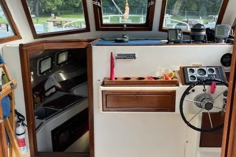 Slide: The Image of 1985 Albin 27 Family boat interior with steering wheel, navigation equipment, and cabin view. - 6