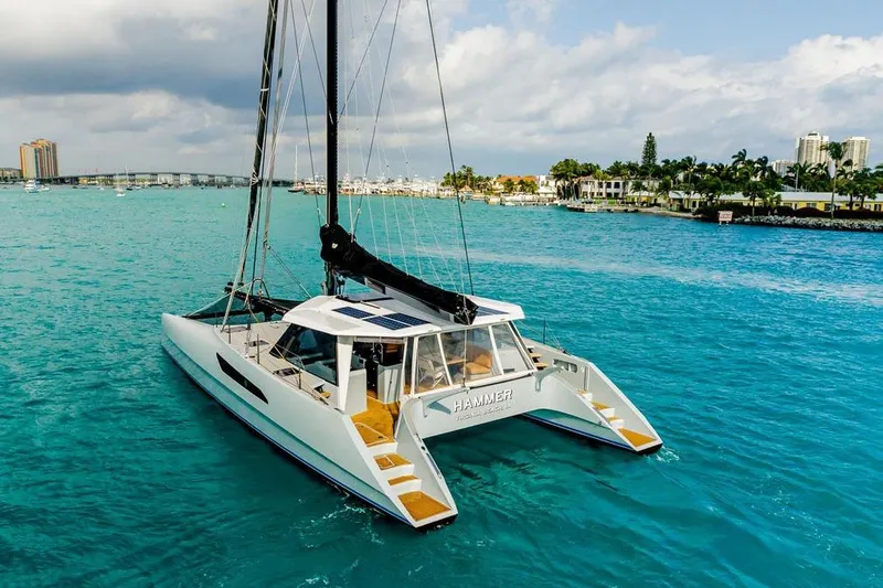 Slide: The Image of 2018 Gunboat 57 catamaran sailing in turquoise waters near a coastal city. - 10