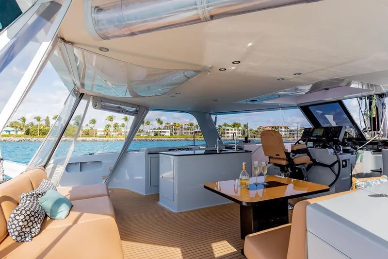 Slide: The Image of Luxurious 2018 Gunboat 57 yacht interior with seating, table, and helm, overlooking scenic waterfront. - 15
