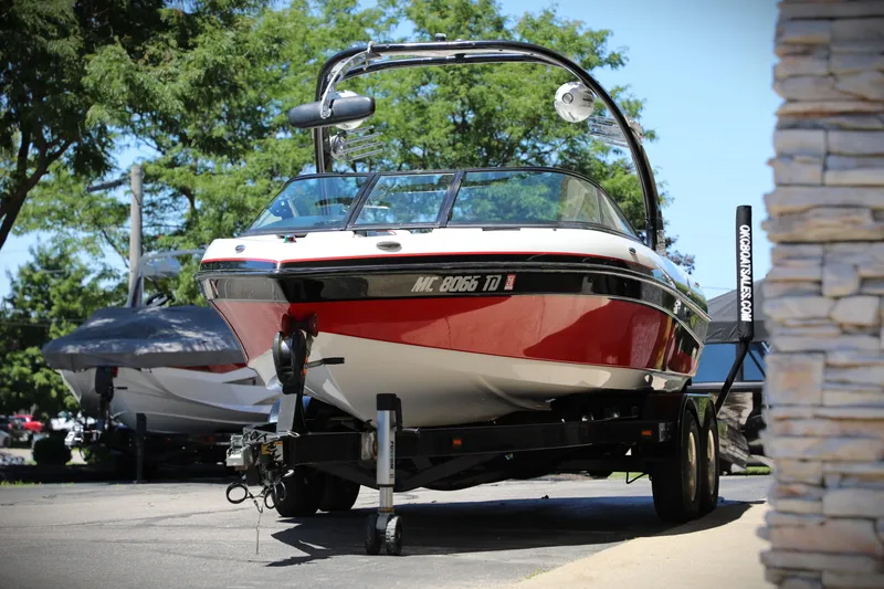 Slide: The Image of 2008 Malibu 21 vRide boat on trailer, parked outdoors with trees in background. - 3