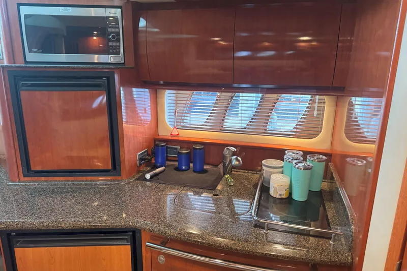 Slide: The Image of Interior of 2006 Sea Ray 380 Sundancer yacht kitchen with granite countertops and wooden cabinetry. - 16
