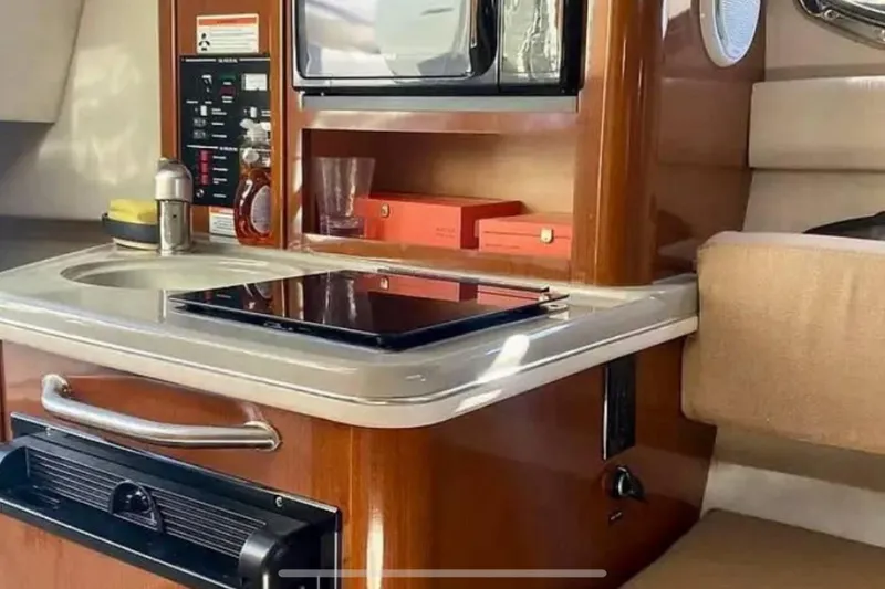 Slide: The Image of 2011 Sea Ray 240 Sundancer cabin interior with kitchenette and seating area. - 11