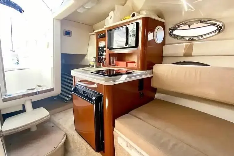 Slide: The Image of Interior of 2011 Sea Ray 240 Sundancer boat with kitchenette and seating area. - 14