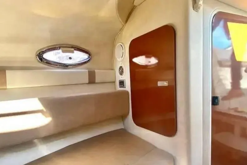 Slide: The Image of Interior cabin of 2011 Sea Ray 240 Sundancer boat, featuring cozy seating and wooden accents. - 15