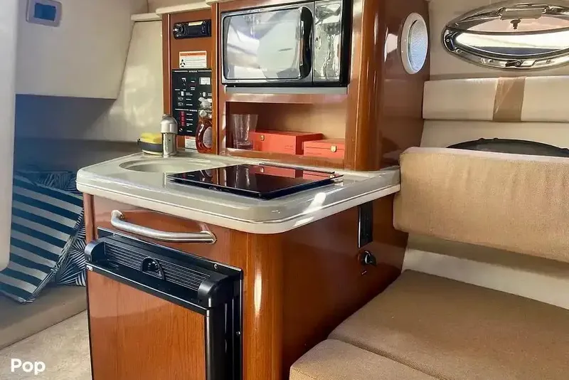 Slide: The Image of Interior of 2011 Sea Ray 240 Sundancer boat with kitchenette and seating area. - 18