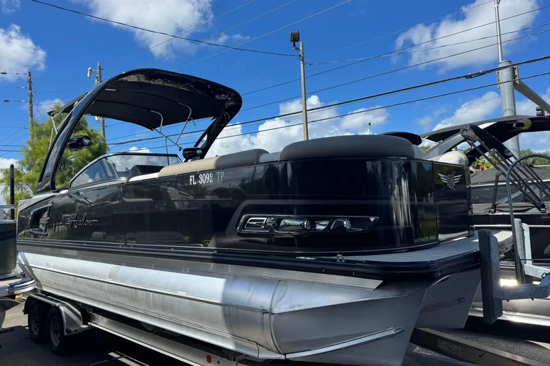 The Image of 2023 Avalon Excalibur 27' pontoon boat on trailer under blue sky. - 0