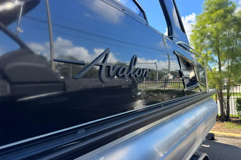 Slide: The Image of 2023 Avalon Excalibur 27' boat with sleek black exterior and logo detail. - 3