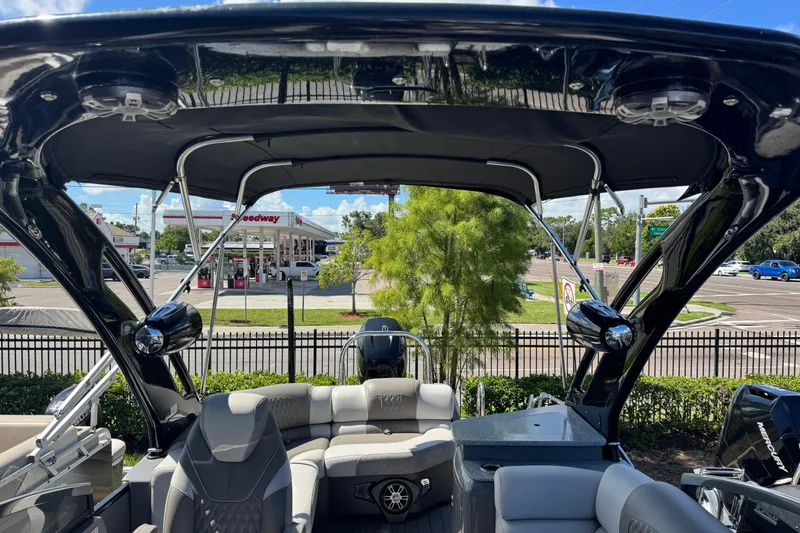 Slide: The Image of 2023 Avalon Excalibur 27' boat interior with seating and canopy, parked near a gas station. - 30