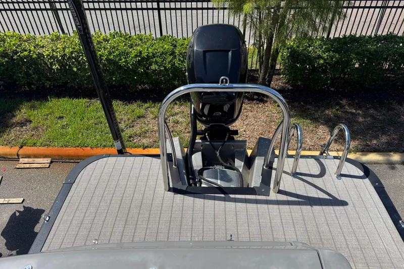 Slide: The Image of 2023 Avalon Excalibur 27' boat with motor and ladder, parked near greenery. - 38