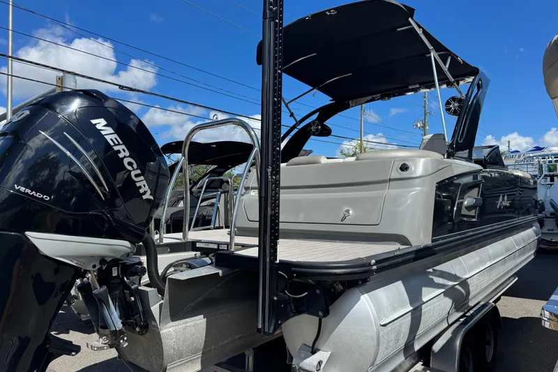 Slide: The Image of 2023 Avalon Excalibur 27' pontoon boat with Mercury Verado engine, docked under blue sky. - 7