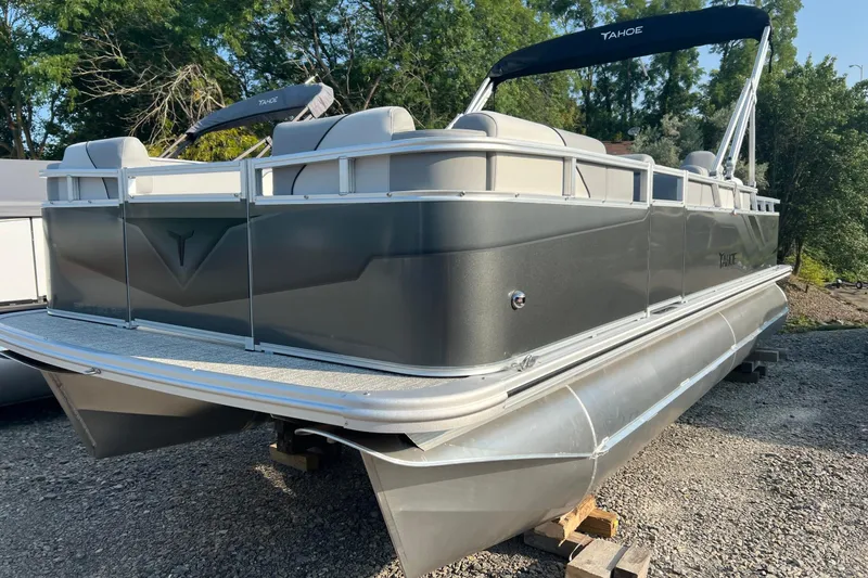 The Image of 2026 Tahoe Pontoon 2180 REAR FISH boat on gravel, featuring sleek design and spacious seating. - 1