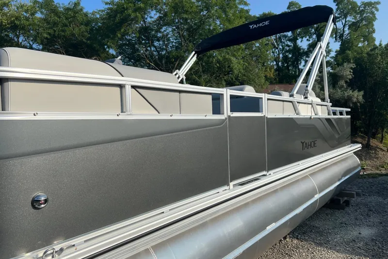 Slide: The Image of 2026 Tahoe Pontoon 2180 REAR FISH boat with canopy, parked on gravel, surrounded by trees. - 12