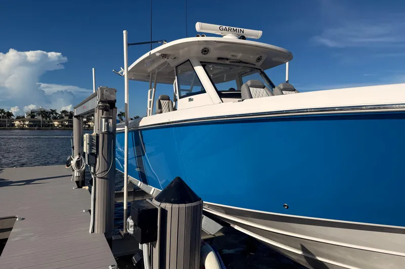 Slide: The Image of 2023 Everglades 395 Center Console boat docked, featuring a sleek blue hull. - 14