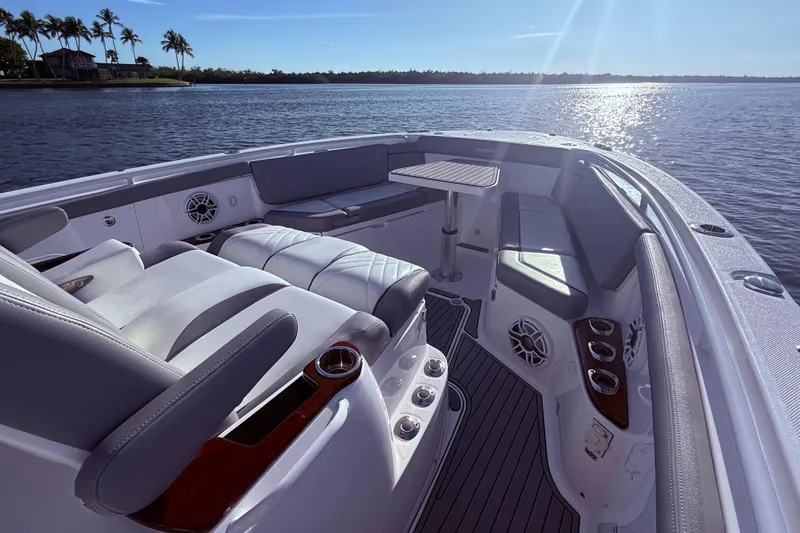 Slide: The Image of 2023 Everglades 395 Center Console boat interior with seating and table on a sunny day. - 27