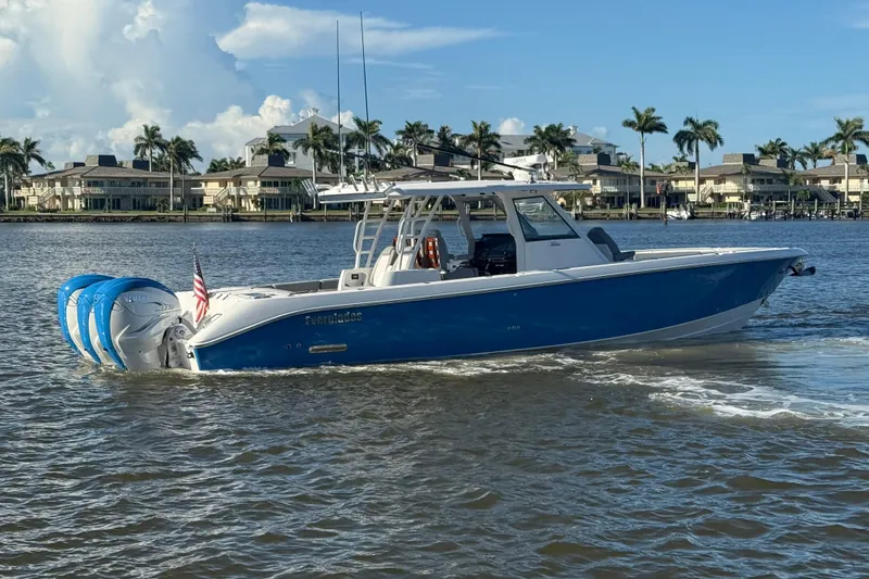 Slide: The Image of 2023 Everglades 395 Center Console boat cruising on a sunny waterfront with palm trees. - 3