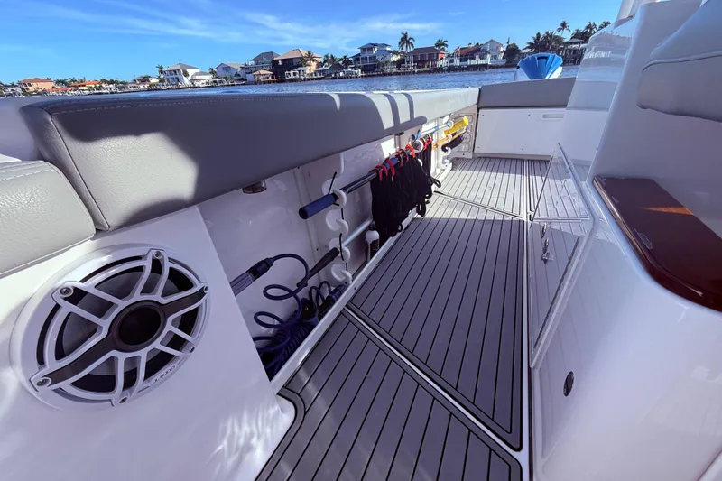 Slide: The Image of 2023 Everglades 395 Center Console boat interior with storage and speaker, docked by waterfront homes. - 38