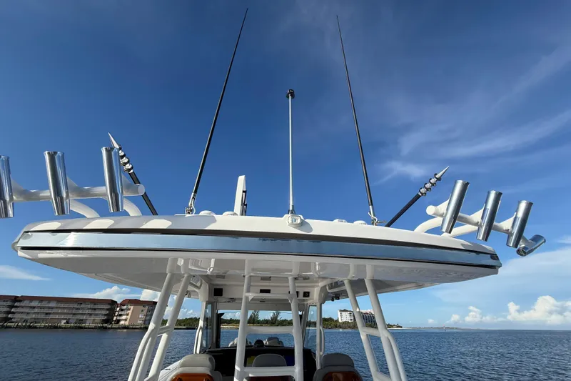 Slide: The Image of 2023 Everglades 395 Center Console boat with fishing rod holders, under clear blue sky. - 64