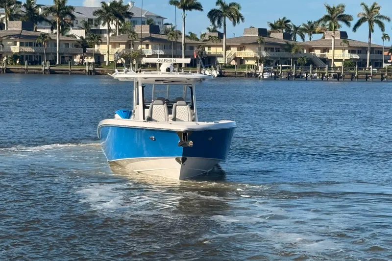 Slide: The Image of 2023 Everglades 395 Center Console boat cruising on a sunny waterfront. - 7