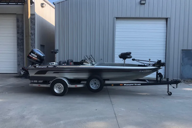 Slide: The Image of 1993 Ranger Comanche 482v boat with Yamaha motor on trailer, parked outside a building. - 1