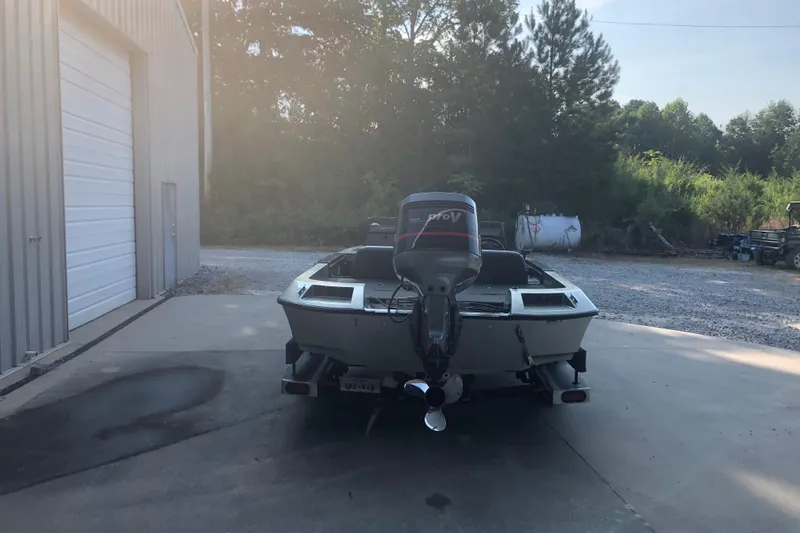 Slide: The Image of 1993 Ranger Comanche 482v boat with outboard motor parked near a garage. - 4
