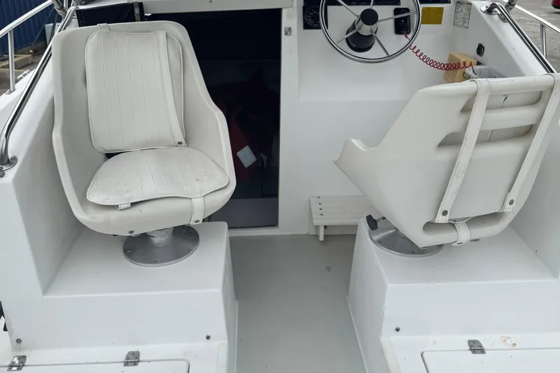Slide: The Image of 1993 Angler 22 Walk Around boat interior with two white swivel seats and steering wheel. - 5