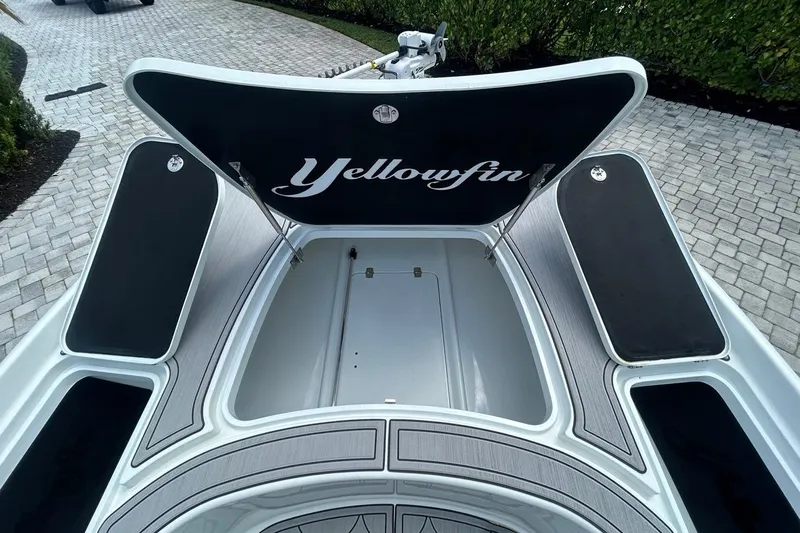 Slide: The Image of 2016 Yellowfin 24 Bay boat with open storage compartments on a paved driveway. - 12