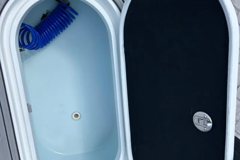 Slide: The Image of Open storage compartment on 2016 Yellowfin 24 Bay boat with blue coiled hose. - 17