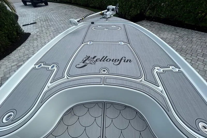 Slide: The Image of 2016 Yellowfin 24 Bay boat deck with custom design and logo, parked on a paved driveway. - 26