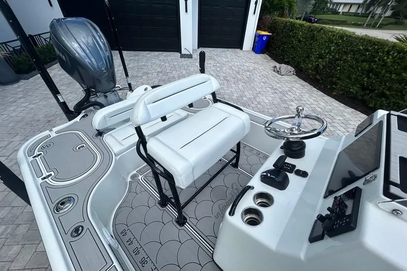 Slide: The Image of 2016 Yellowfin 24 Bay boat interior with steering wheel and seating, parked on a paved driveway. - 29