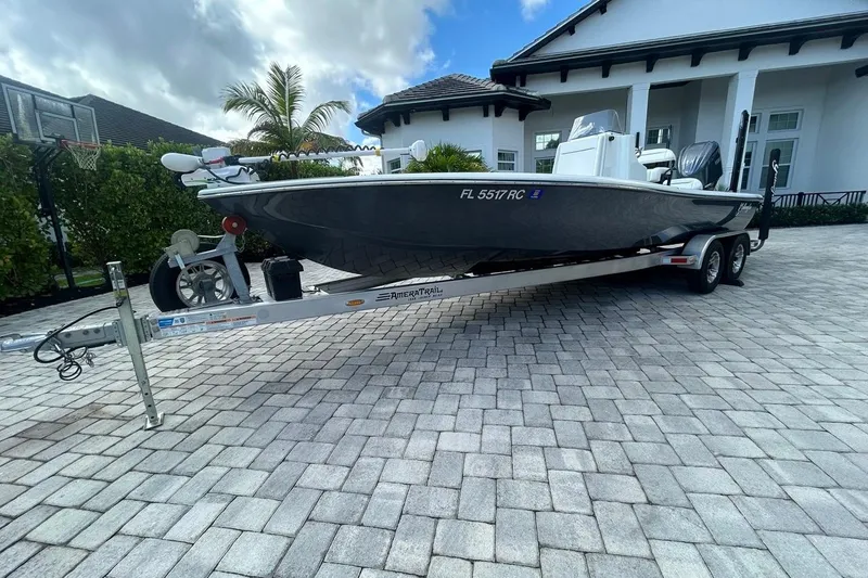 Slide: The Image of 2016 Yellowfin 24 Bay boat on trailer in driveway, surrounded by greenery and modern house. - 31