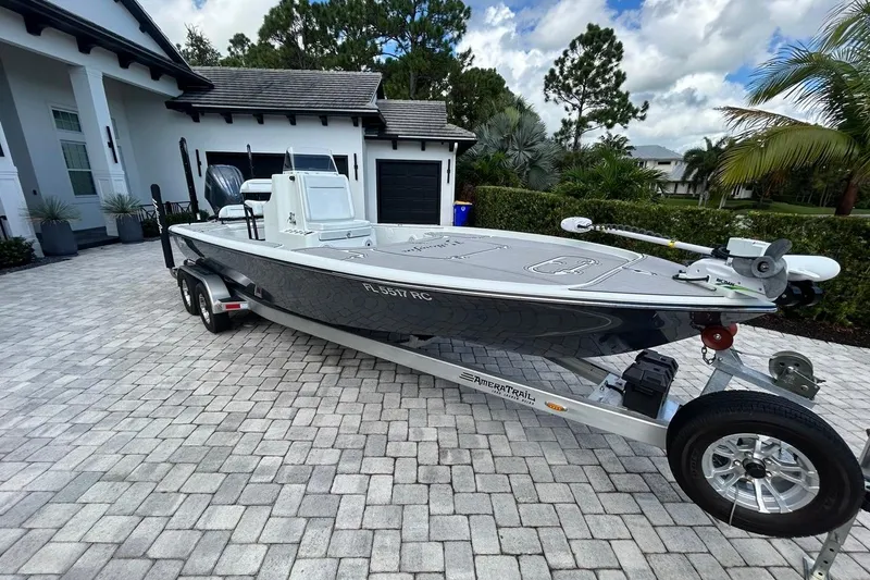 Slide: The Image of 2016 Yellowfin 24 Bay boat on trailer in driveway, surrounded by lush greenery. - 32