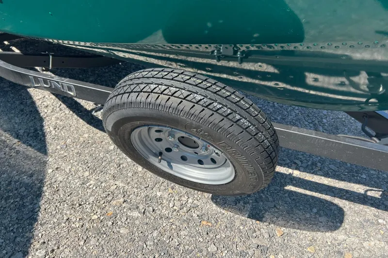 Slide: The Image of Trailer tire of 2026 Lund 1650 Angler SS boat on gravel surface. - 6