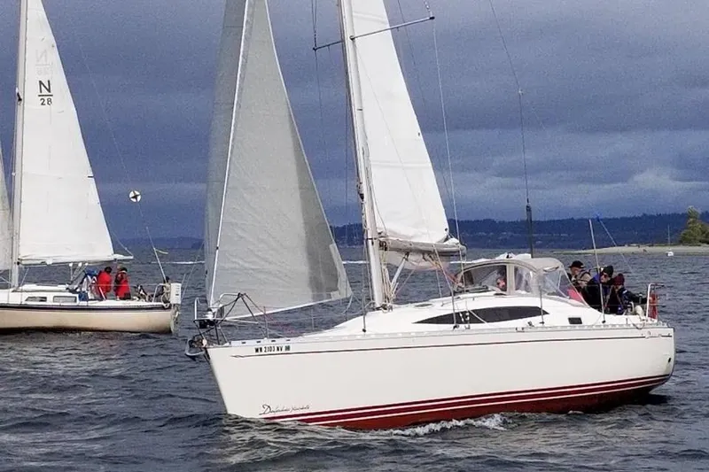 Slide: The Image of 2007 Delphia 33 sailboat navigating calm waters under cloudy skies. - 1
