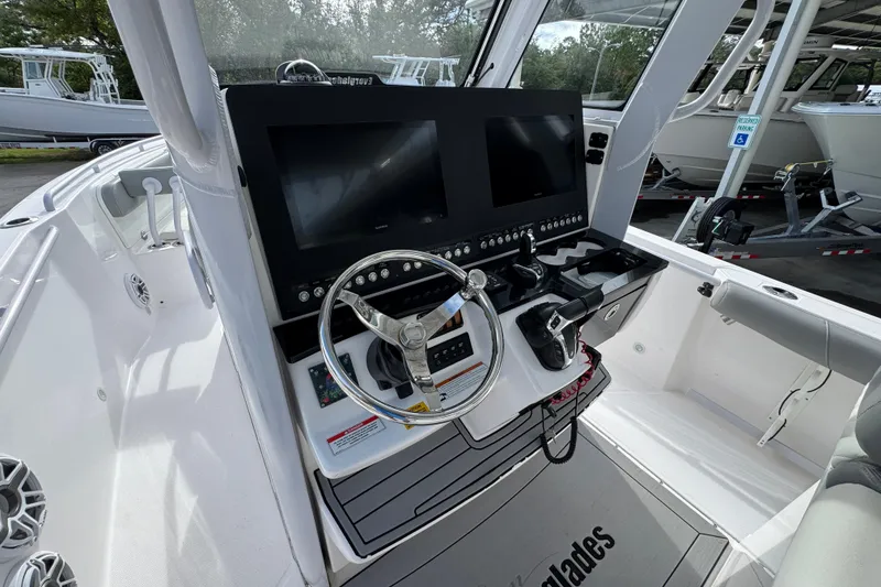 Slide: The Image of 2022 Everglades 295 Center Console boat dashboard with dual screens and steering wheel. - 32