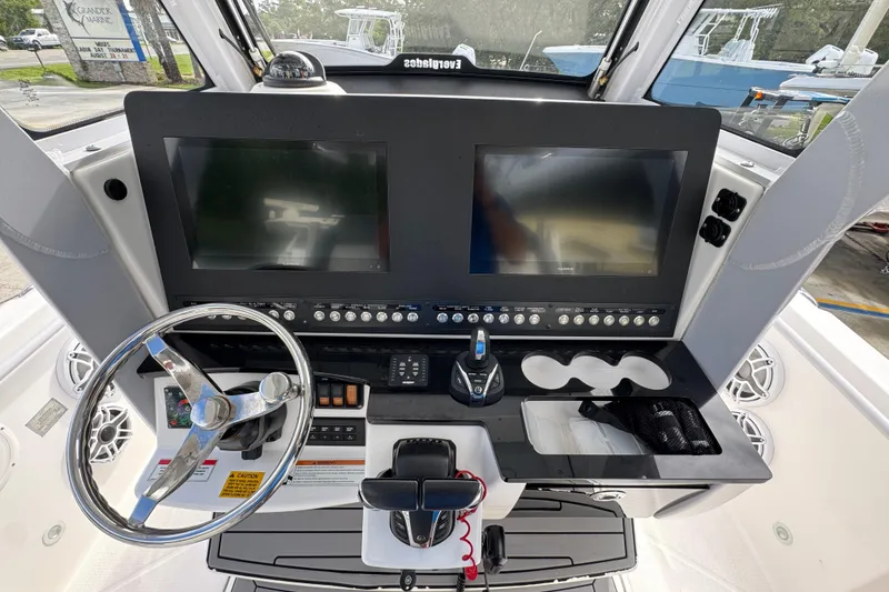 Slide: The Image of 2022 Everglades 295 Center Console boat dashboard with dual screens and steering wheel. - 33
