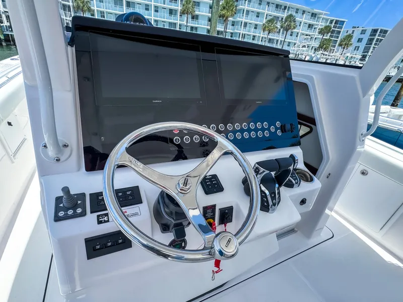 Slide: The Image of 2025 Edgewater 370CC helm with modern controls and dual displays, dockside view. - 15