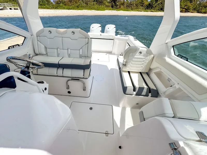 Slide: The Image of 2025 Edgewater 262 CX boat interior with white seating, near a scenic shoreline. - 8