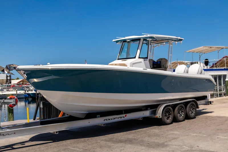 The Image of 2025 Edgewater 325CC boat on trailer at marina, clear blue sky background. - 0