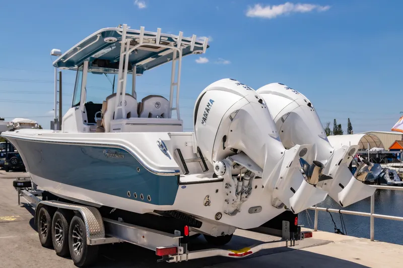 Slide: The Image of 2025 Edgewater 325CC boat on trailer with dual outboard engines, dockside view. - 2