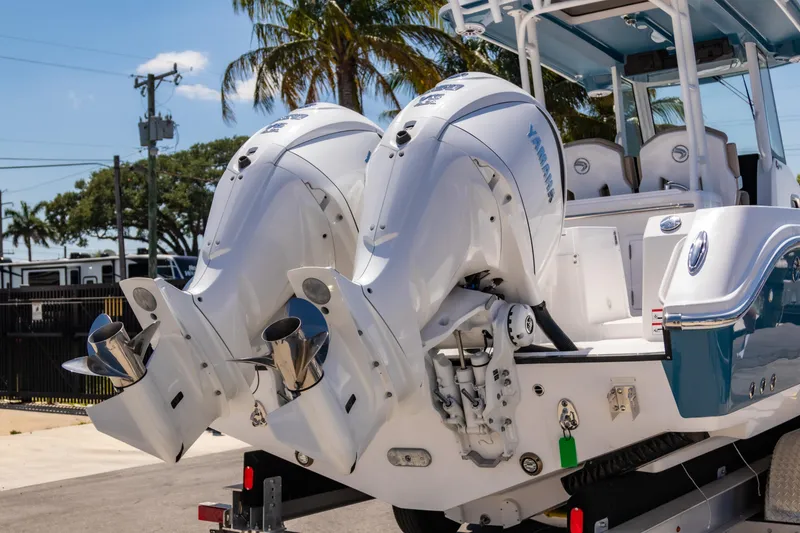 Slide: The Image of 2025 Edgewater 325CC boat with dual Yamaha outboard engines, parked near palm trees. - 3