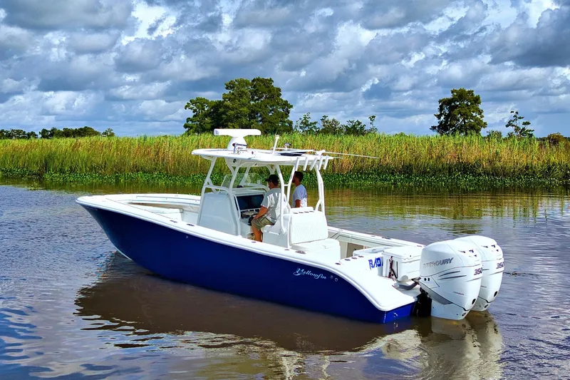 Slide: The Image of 2017 Yellowfin 32 Offshore boat on calm water, surrounded by lush greenery. - 3