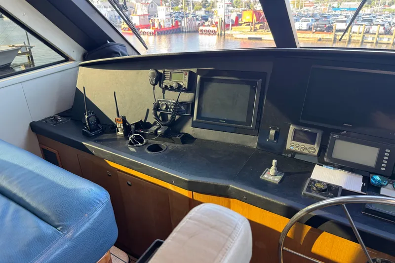 Slide: The Image of 2002 Viking 61 Enclosed Bridge helm with navigation equipment and marina view. - 43