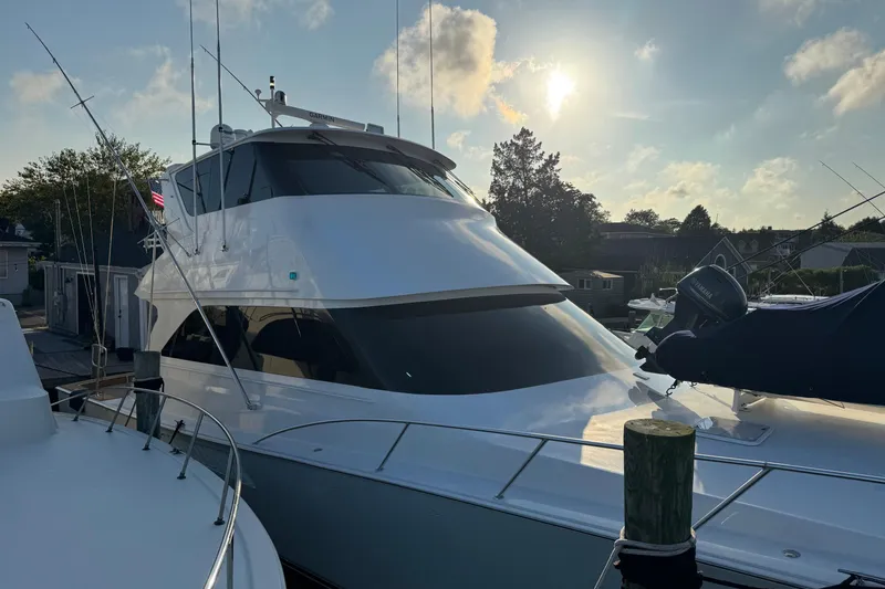 Slide: The Image of 2002 Viking 61 Enclosed Bridge yacht docked at sunset, featuring sleek design and fishing equipment. - 5