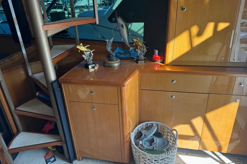 Slide: The Image of Interior of 2002 Viking 61 Enclosed Bridge with wooden cabinets and decorative fish trophies. - 54