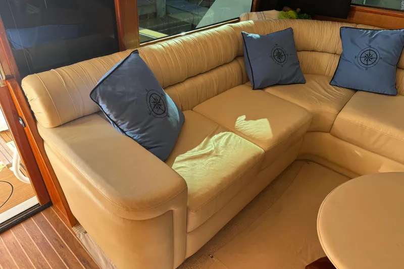 Slide: The Image of Luxurious beige leather seating with blue nautical pillows on a 2002 Viking 61 Enclosed Bridge yacht. - 57