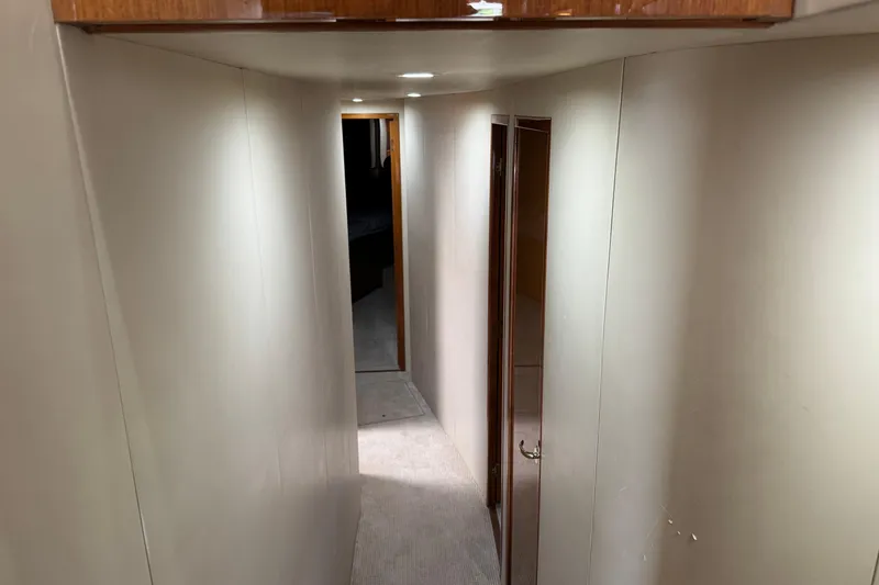 Slide: The Image of Narrow hallway inside 2002 Viking 61 Enclosed Bridge yacht, featuring wooden accents and soft lighting. - 67