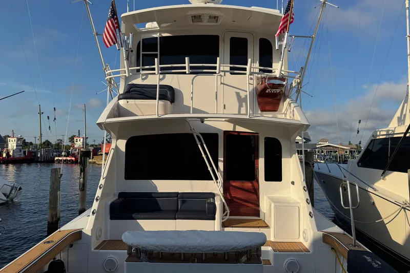 Slide: The Image of 2002 Viking 61 Enclosed Bridge yacht docked at marina, featuring spacious deck and American flags. - 7
