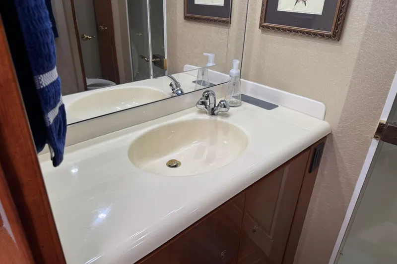 Slide: The Image of Bathroom sink area in 2002 Viking 61 Enclosed Bridge yacht, featuring mirror and soap dispenser. - 77