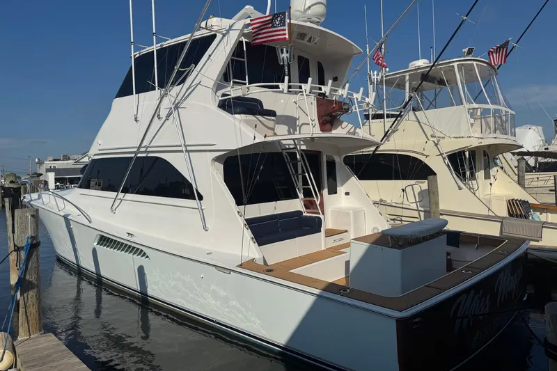 Slide: The Image of 2002 Viking 61 Enclosed Bridge yacht docked, featuring sleek design and American flags. - 9